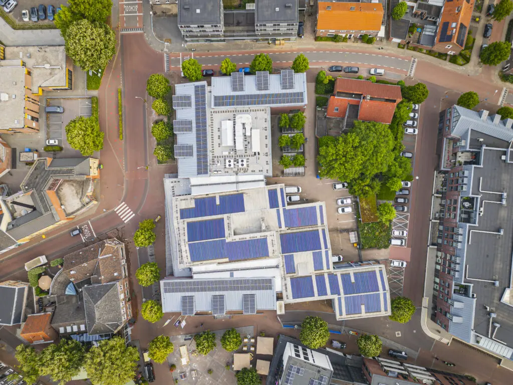 Gemeentehuis Horst van boven met zonnepanelen op het dak en laadpalen op parkeerterrein
