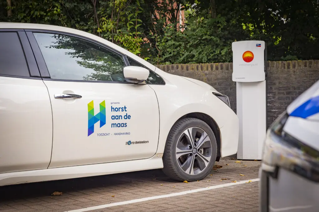 Witte auto van de gemeente Horst aangesloten op een laadpaal op eigen terrein